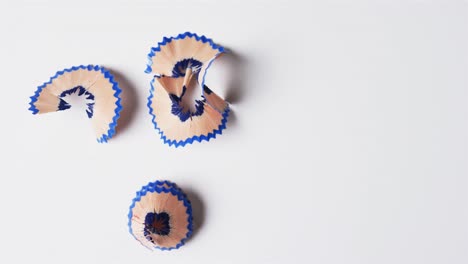 overhead view of blue crayon shavings with copy space on white background, in slow motion