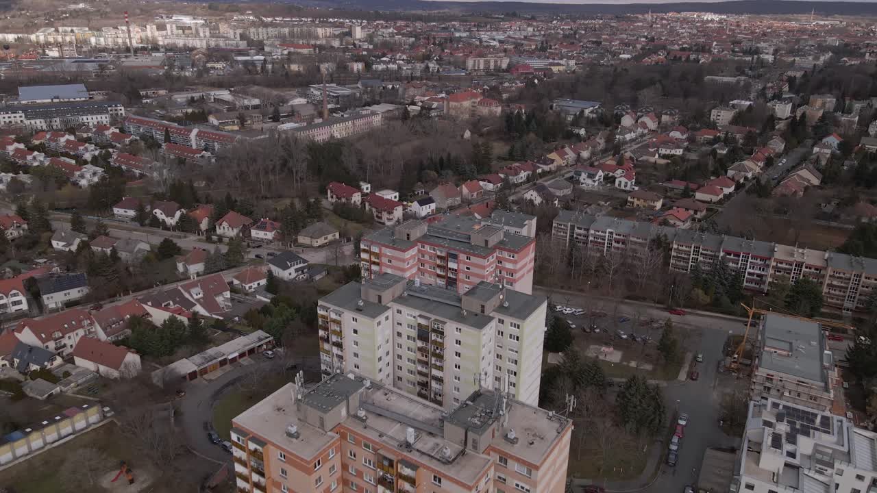 Flying over with a drone three residential apartment buildings in the middle of a town.