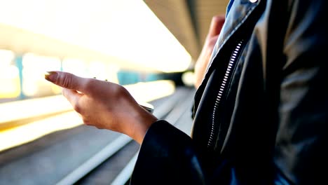 mujer usando teléfono móvil en la estación de tren 4k