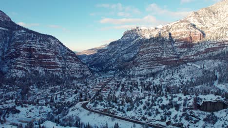 sunrise drone aerial flyover of ouray, colorado in the winter covered in snow