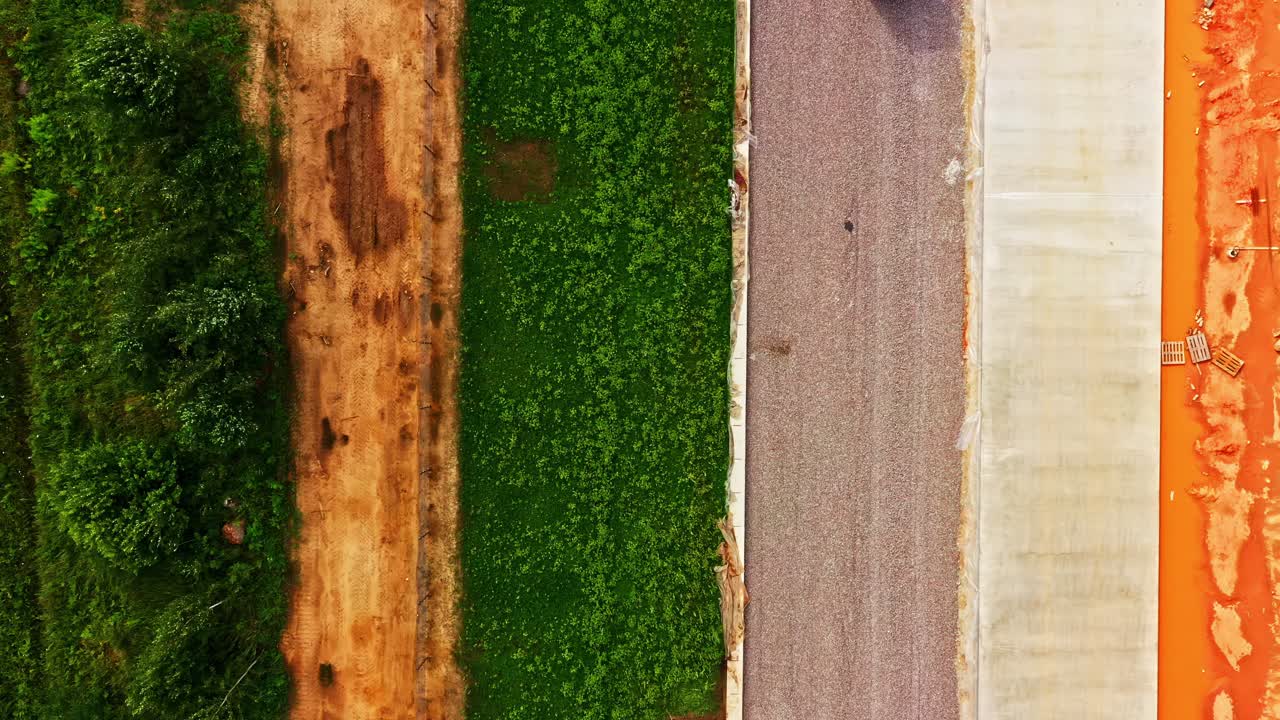 Top-down view of Excavator spreading gravel on railway slope with dumper truck at worksite