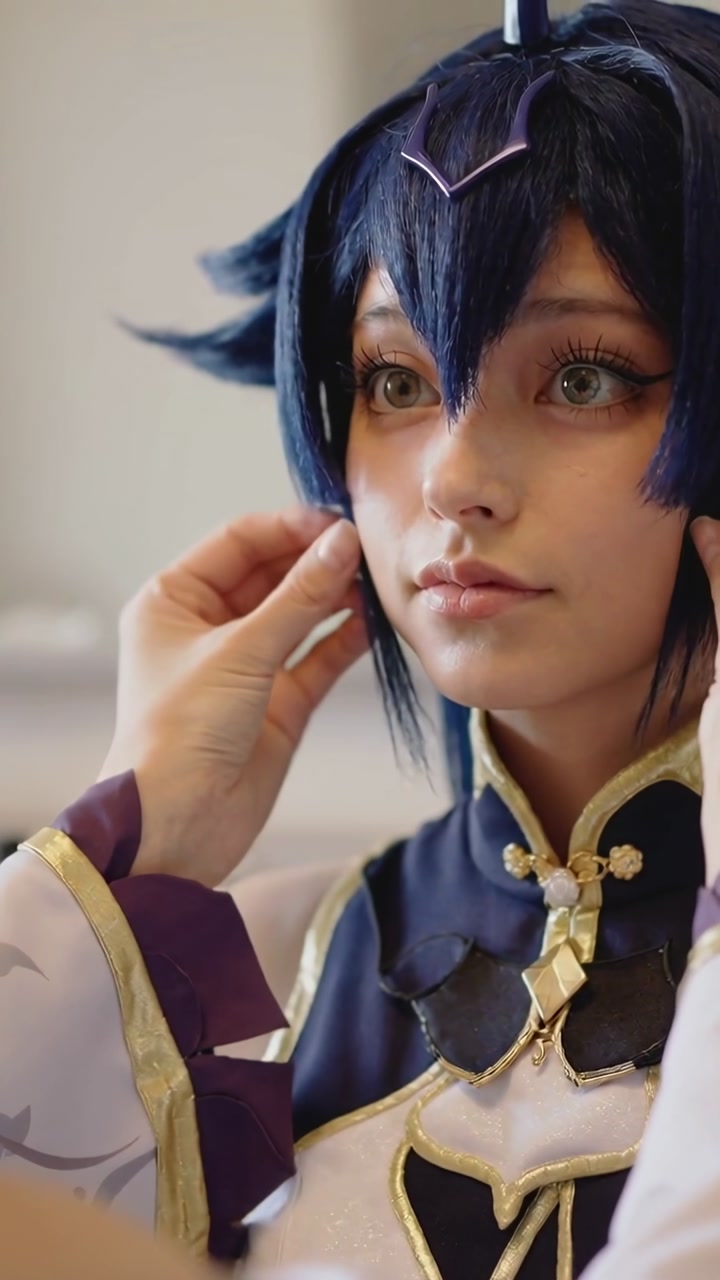 Vertical video: Reaching helper hands tucking cosplayer blue wig at prep for shoot with gold collar