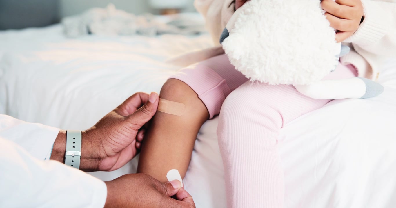 Médico colocando curativo adesivo no joelho de uma criança