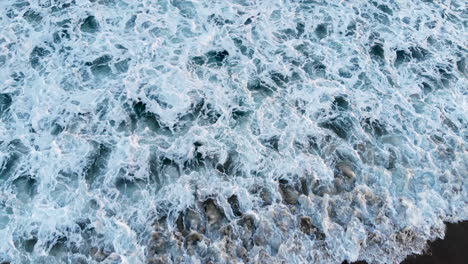 top down shot of beautiful blue waves crashing onto the shore in seal beach, ca