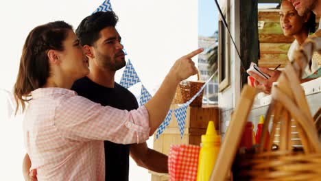 Smiling-waiter-taking-order-from-couple