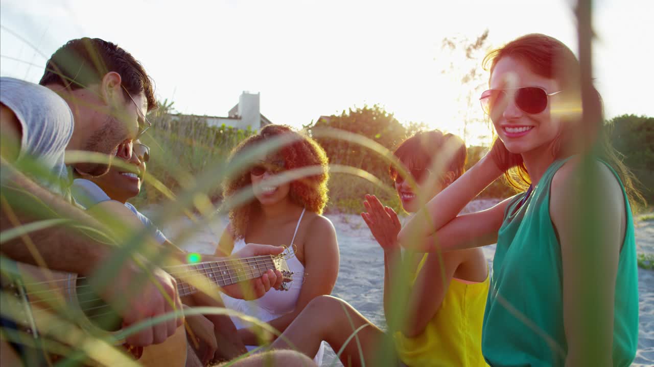 hombre caucásico tocando la guitarra y cantando en la playa
