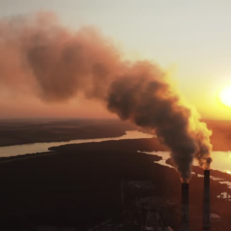 large plant with smoking pipes. dark smoke comes out in clouds from chimney of factory plant