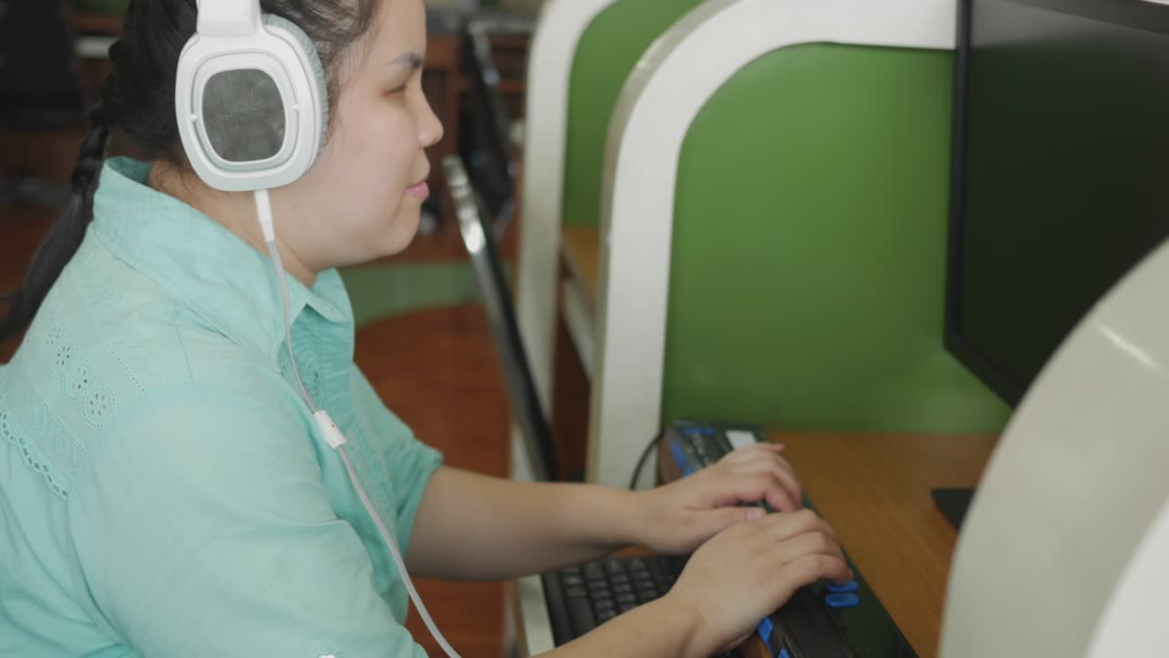 Authentic blind person woman with headphone using computer with braille display assistive device for disabled people with visual impairment.
