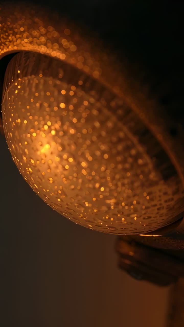 Vídeo vertical: Câmera ajustando o foco, transformando gotas em cúpula em bokeh no banheiro, expondo uma braçadeira.