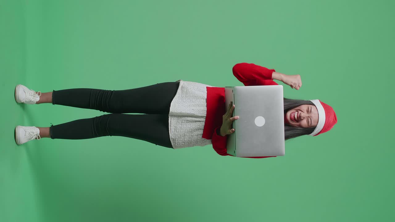 mujer celebrando con una computadora portátil en un suéter de navidad