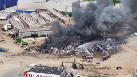 Imágenes-Aéreas-En-Cámara-Lenta-Girando-Alrededor-De-Una-Escena-De-3-Camiones-De-Bomberos-Disparando-Agua-En-Un-Gran-Incendio-Industrial-En-Chattanooga,-Tennessee.