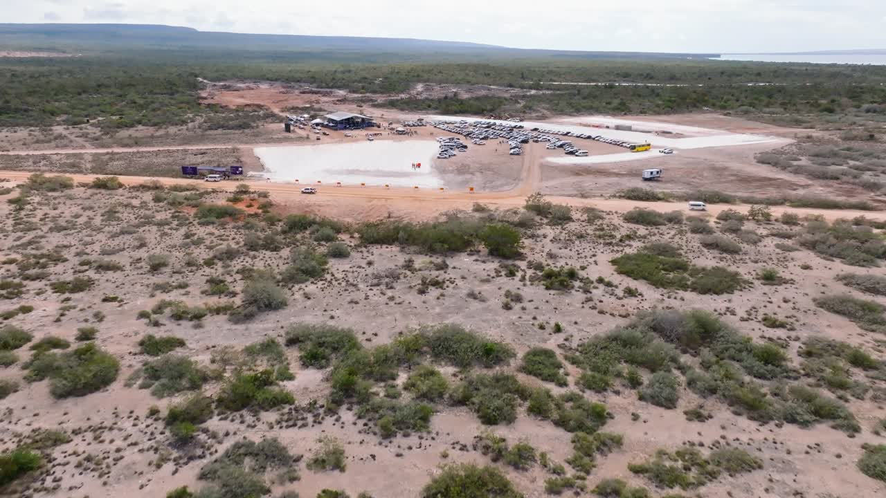 Aerial flyover dry field with bush and parking cars during planning phase of new building area for hotels in pedernales