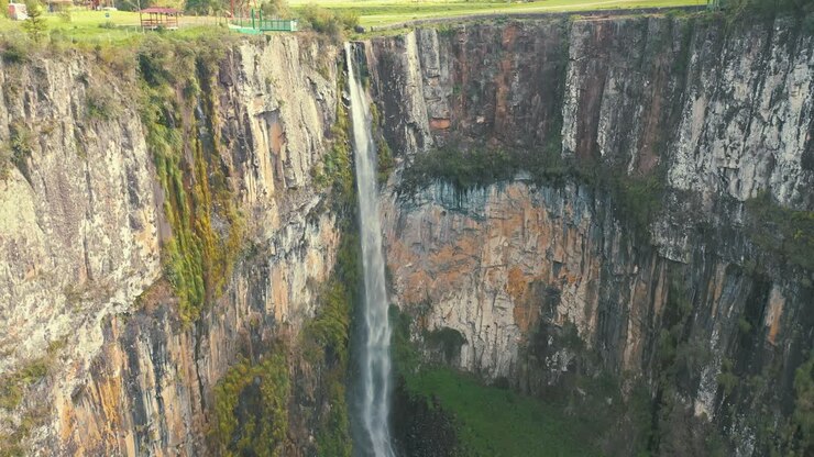 Cascata nella foresta pluviale tropicale con una grande parete rocciosa.