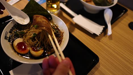 person eating ramen with chopsticks at a table