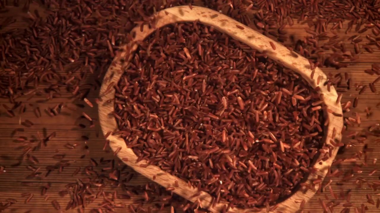 Slow Motion of Red Rice Pouring into a Wooden Bowl