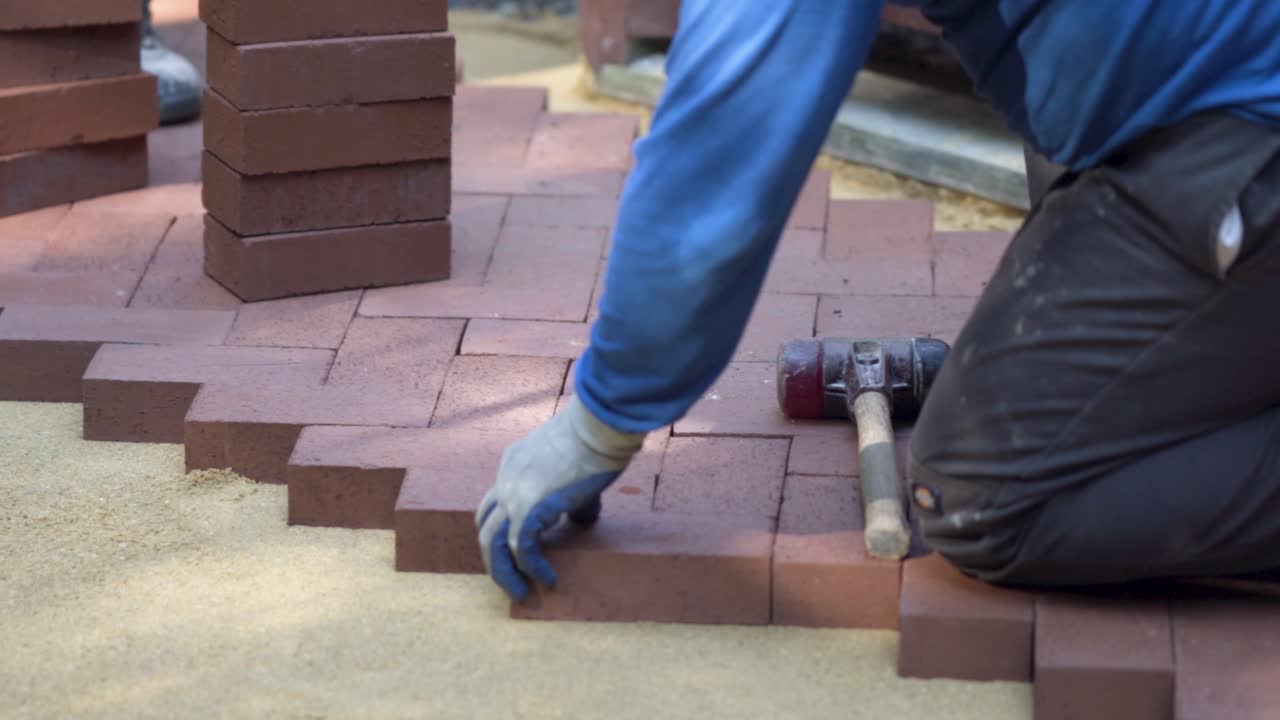 Bricklayer Paving with Bricks and Hammer