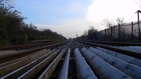 low angle view looking down empty railway tracks under blue cloudy sky