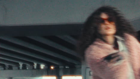 young stylish woman expressively dancing under concrete overpass