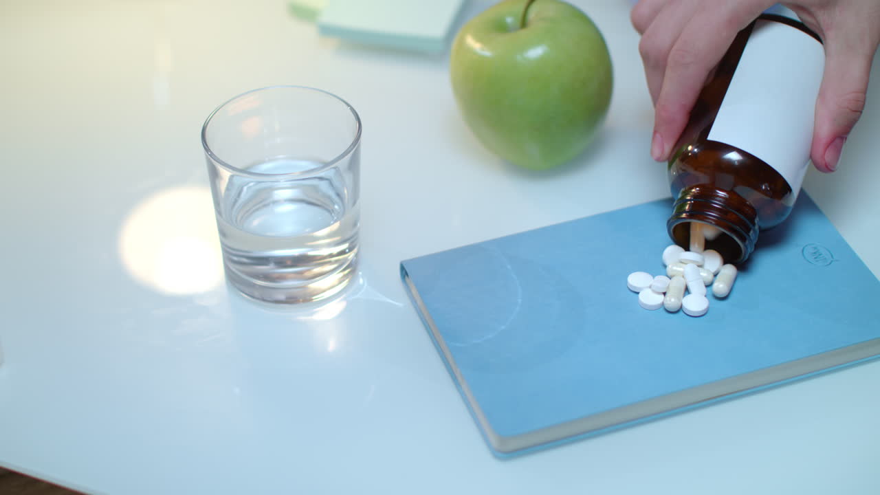 Hand pour tablet and capsules from bottle on table. Healthy medicine concept