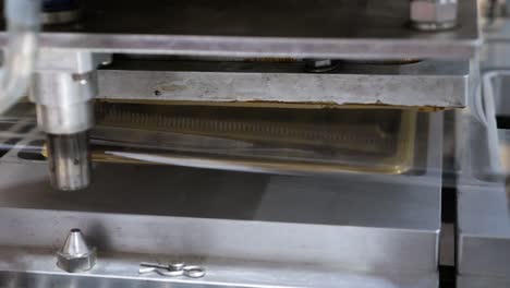 Static-shot-of-plastic-boxes-filled-with-fresh-dates-being-sealed-through-plastic-cover-through-the-machine-inside-a-dates-factory