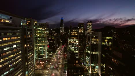 avión no tripulado sobre santiago, chile avenida las condes por la noche calles de rascacielos edificios de altas torres, horizonte al atardecer en la metrópolis latinoamericana