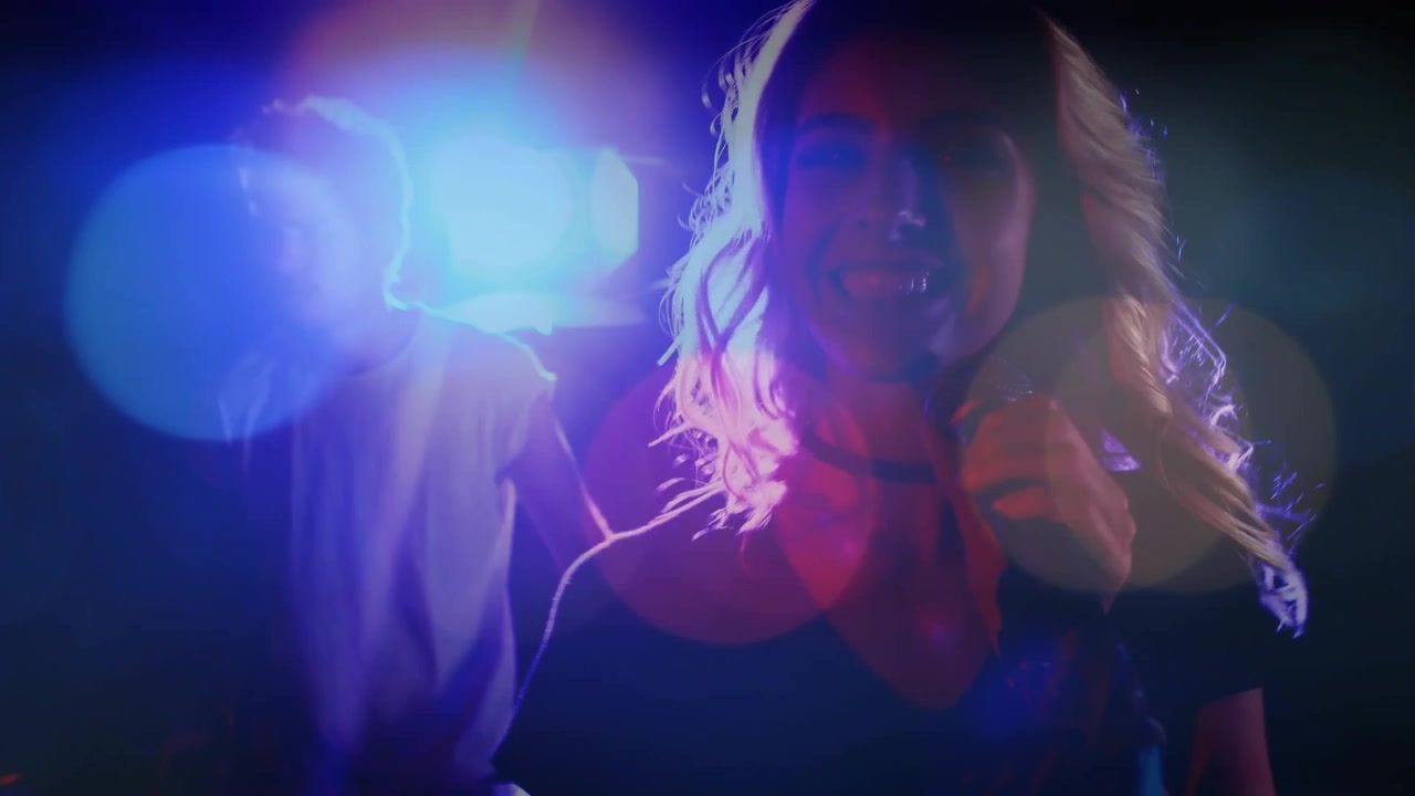 Gegenlicht rückt eine Sängerin ins Rampenlicht, die ein Mikrofon hält und singt; Lens Flares und Bokeh akzentuieren die Musik.