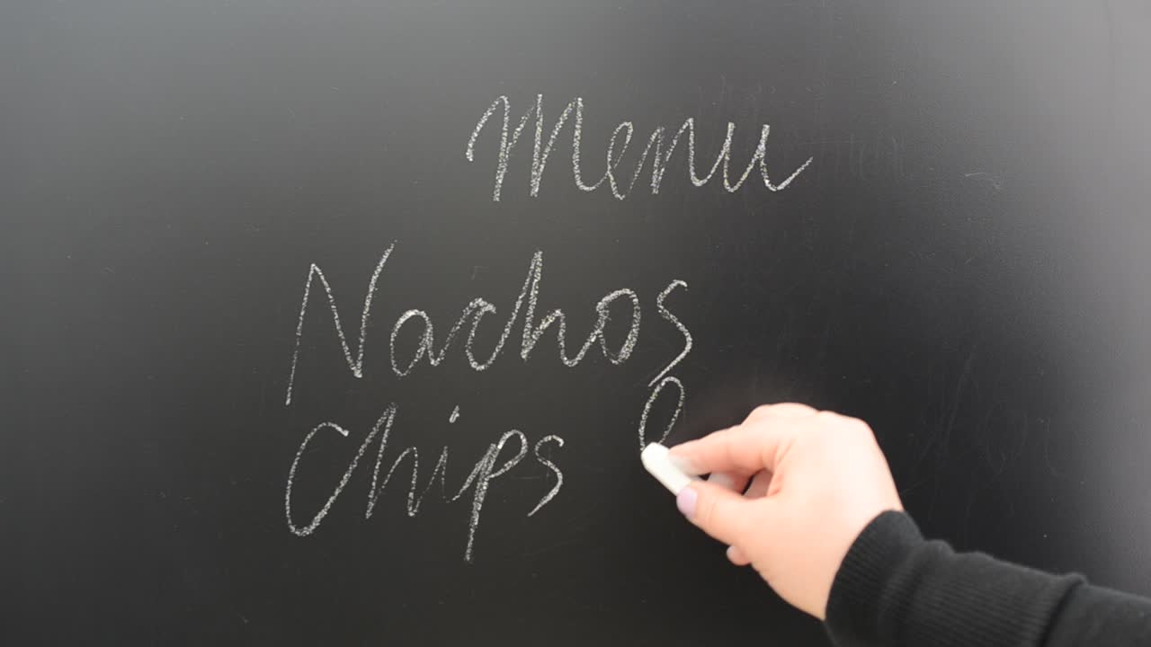 Wir schreiben auf eine Menütafel. Kreideinschrift auf einer Tafel.