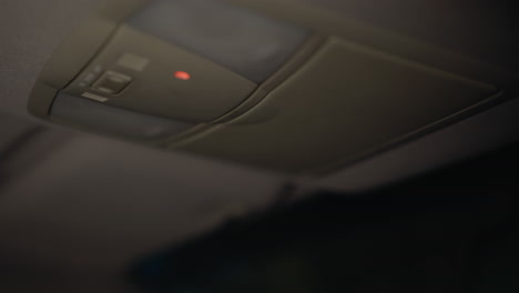 first-person view of a woman closing a car roof box and turning off the interior light at night. hand with black painted nails interacts with the car's roof box and light switched off