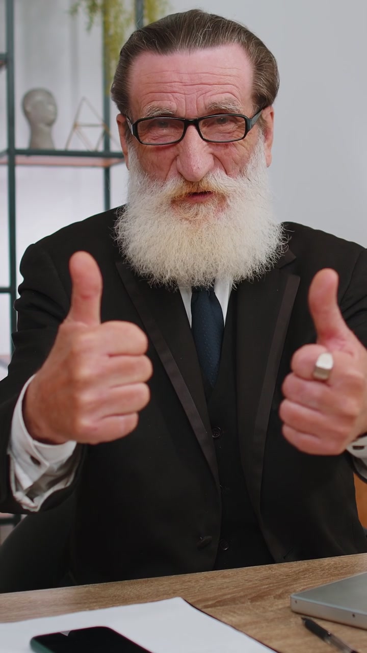 Happy business man looking approvingly at camera showing thumbs up like positive sign good news