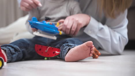 vista de cerca de un bebé irreconocible sentado en el suelo con su madre