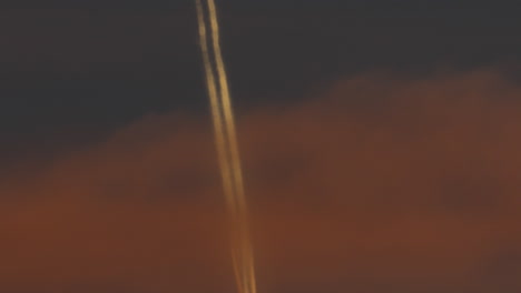 airplane with contrail at orange sunset