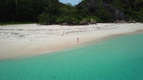 Luftaufnahme-Einer-Frau,-Die-Am-Weißen-Sandstrand-Auf-Der-Tropischen-Insel-Auf-Den-Seychellen-Spazieren-Geht