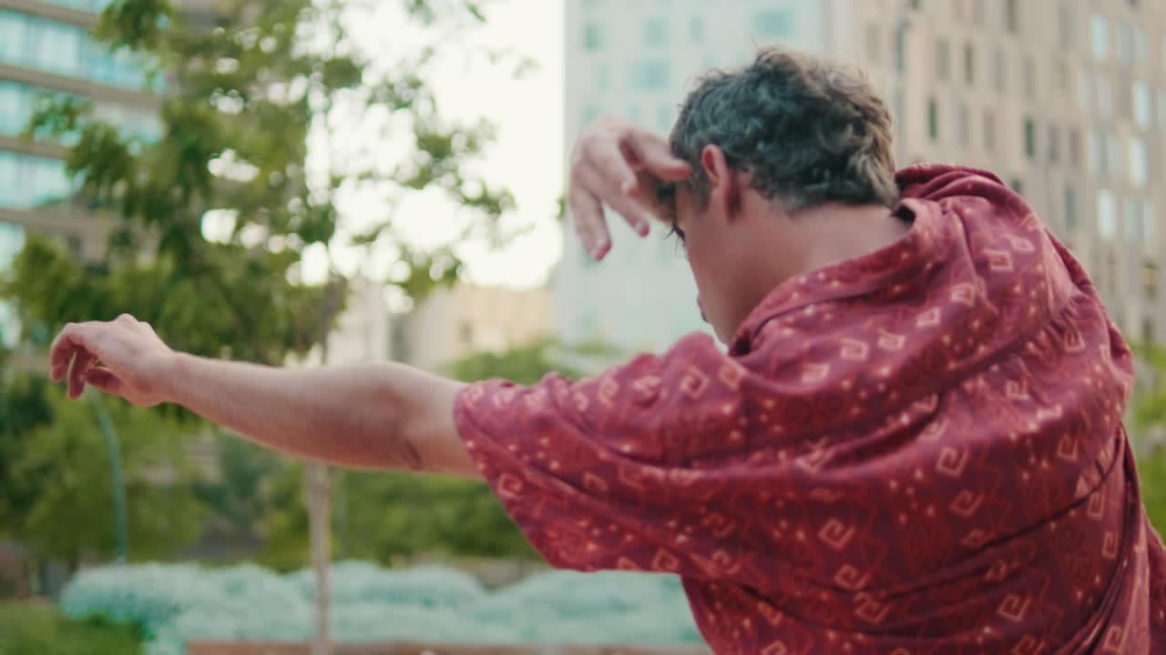Man in Red Shirt Performing Expressive Movements in Urban Park