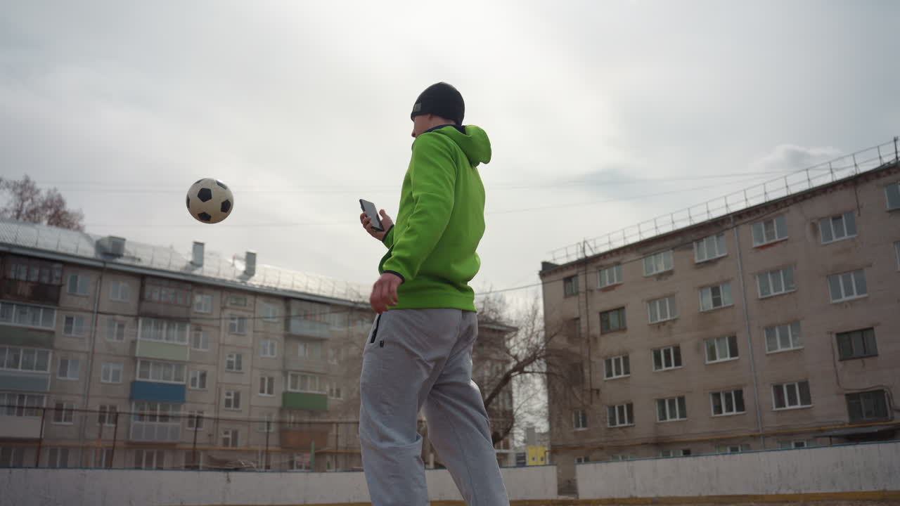 도시를 배경으로 한 축구 선수의 역동적인 샷, 도시 축구장에서 발리킥을 하는 백인 운동 선수, 도시 축구 경기장에서 활기찬 발리슛을 선보이는 밝은 피부색의 선수의 활기 넘치는 장면