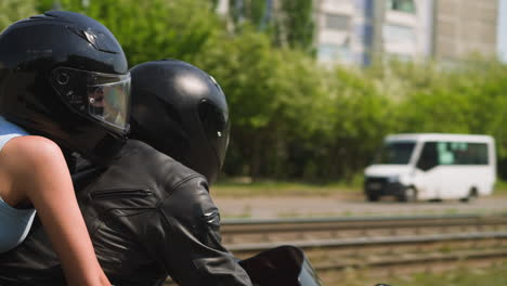 pareja feliz en cascos monta motocicleta a lo largo de la calle de la ciudad