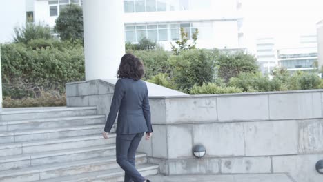 full lenght shot of a middle aged businesswoman in suit walking upstairs to her office building