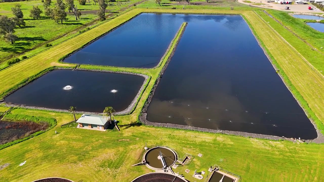 High-angle drone shot of wastewater treatment ponds and circular filtration tanks in Gunnedah, Australia.