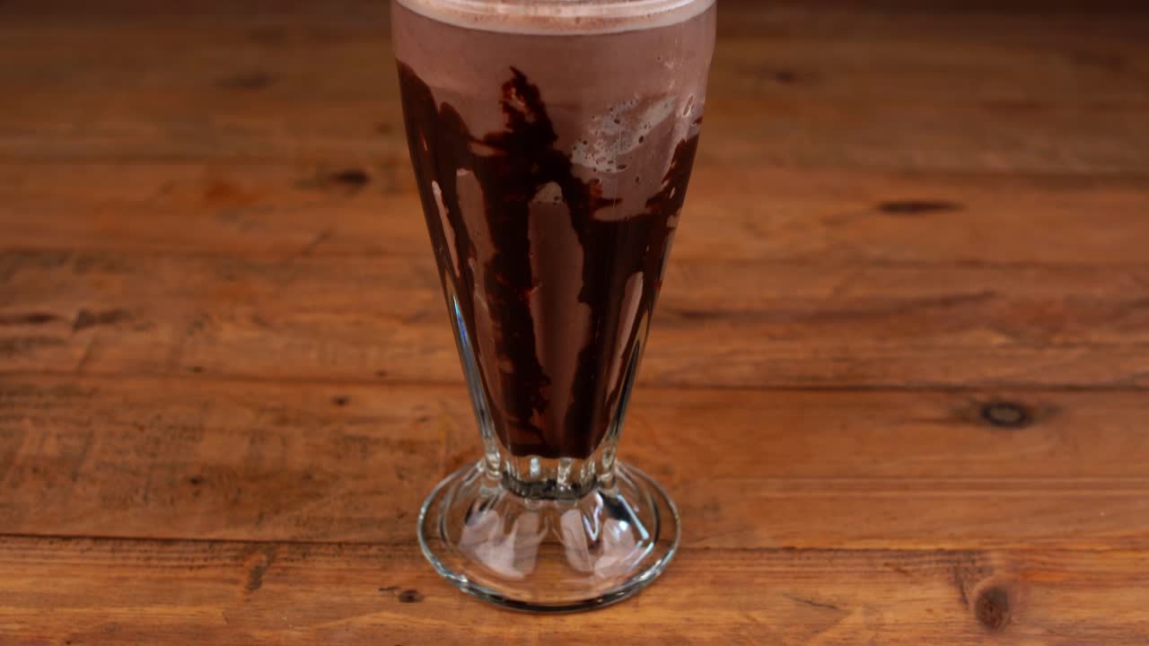 primer plano detallado de batido de chocolate, con caramelo, café espresso y crema batida con cereza, inclinar hacia arriba y hacia abajo