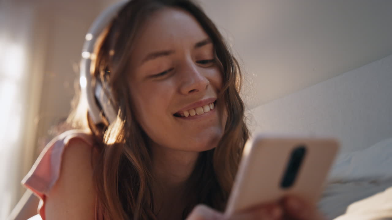 Primo piano di ragazza adolescente che ascolta musica con le cuffie. Donna felice che digita un messaggio.