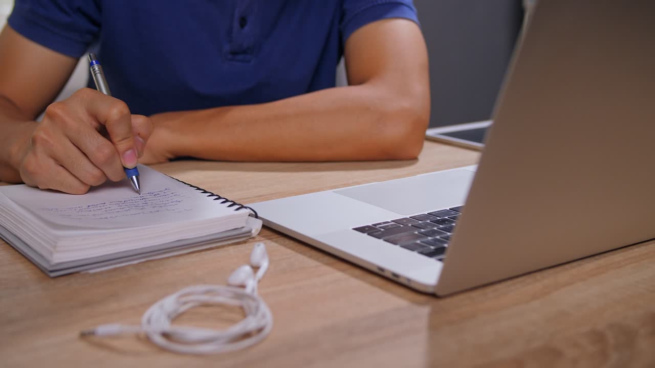 Person Studying at a Desk with Laptop and Notebook