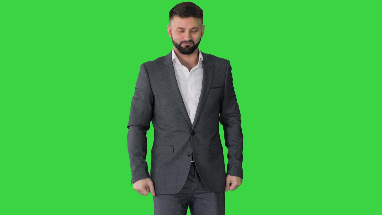 un hombre de negocios barbudo con el pulgar hacia arriba en una pantalla verde, llave de croma