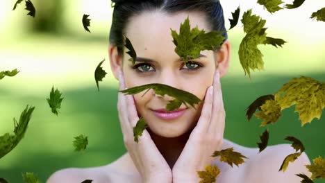 animation of leaves over close-up of beautiful smiling caucasian woman standing in park