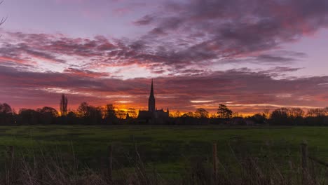 sun rising behind salisbury cathedral. filmed from town path overlooking harnham water meadows. filmed on 23rd february 2021. salisbury is a lovely medieval cathedral city