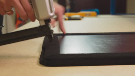 employee fixes fabric covering on furniture details in shop