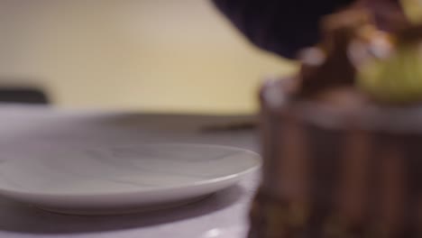 primer plano de una persona en casa cortando una rebanada de pastel de celebración de chocolate en la mesa 4