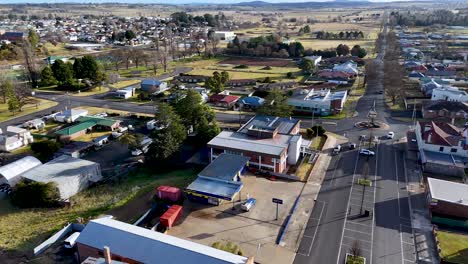 drone footage moves above a quiet city junction in glen innes, australia, showing commercial buildings, residential homes, and clear winter daylight with steady camera motion