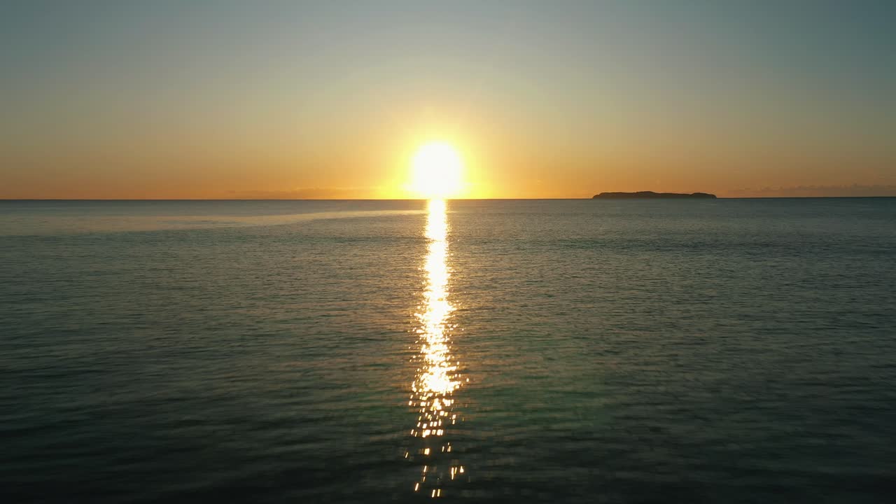 Flying backwards near the water over the ocean sunrise