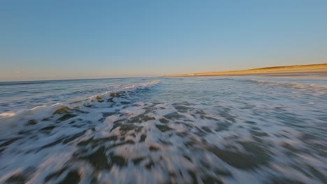 Spectacular-FPV-drone-shot-flying-closely-over-breaking-waves-at-very-high-speed-during-sunset