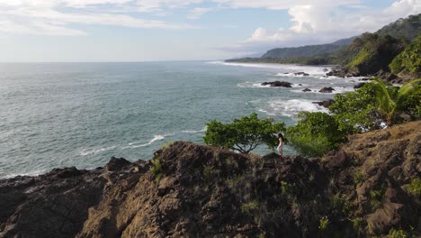 señora caminando sobre el borde del acantilado con vista al mar en costa rica