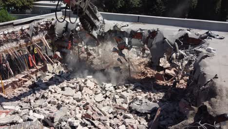 aerial orbiting shot of a crane demolishing the remains of a building